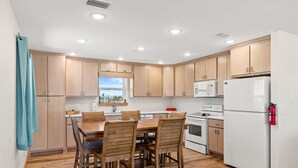 Une cuisine moderne avec des meubles en bois, un réfrigérateur blanc et une table à manger avec des chaises.