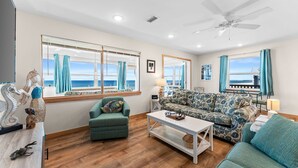 Un salon avec vue sur la mer, un ventilateur de plafond et un canapé.