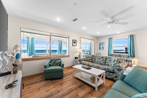 Ein Wohnzimmer mit Meerblick, Deckenventilator und einer Couch.