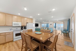 A modern kitchen with wooden cabinets, a dining table with chairs, and a large window overlooking the sea. - Stunning Beachfront Mexico Beach| 6 BR, Sleeps 18 (Mexico Beach)