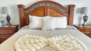 A neatly made bed with a wooden headboard, two bedside tables with lamps, and a decorative pillow arrangement. - Walker Ridge Hideout Pets Pool Table (Montrose)