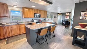A modern kitchen with wooden cabinets, a granite countertop, and a central island with bar stools. - Walker Ridge Hideout Pets Pool Table (Montrose)