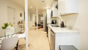 A modern kitchen with white cabinets, a glass dining table, and a built-in oven. - 2 bedroom sanctuary in the middle of Washington DC (Washington)