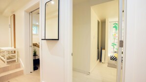A hallway with a white wall, a mirror, and a staircase leading to a room. - 2 bedroom sanctuary in the middle of Washington DC (Washington)