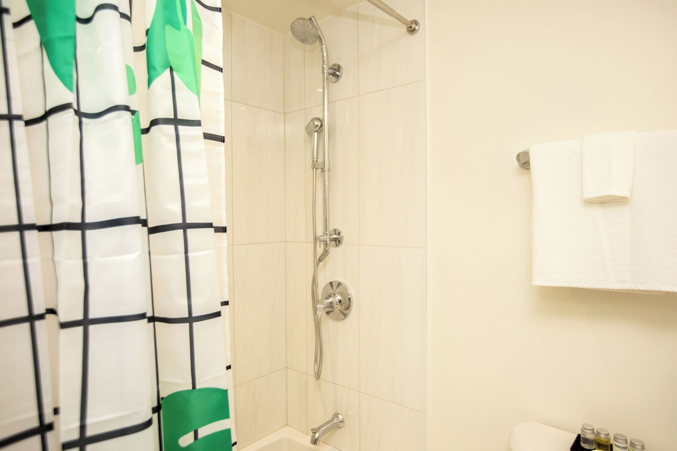 Un baño con ducha, una silla verde y un perchero.