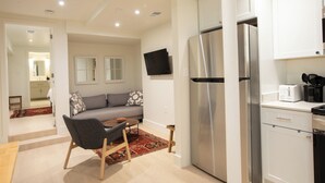 A modern kitchen with stainless steel appliances, a dining area with a sofa and coffee table, and a flat-screen TV mounted on the wall. - 2 bedroom sanctuary in the middle of Washington DC (Washington)