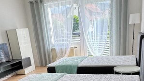 Une chambre d’hôtel avec deux lits, une petite table, un téléviseur et une vue sur l’extérieur.