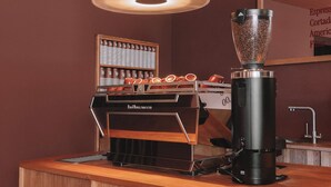 En café med en kværn, en kaffemaskine og et udstilling af kaffekopper.