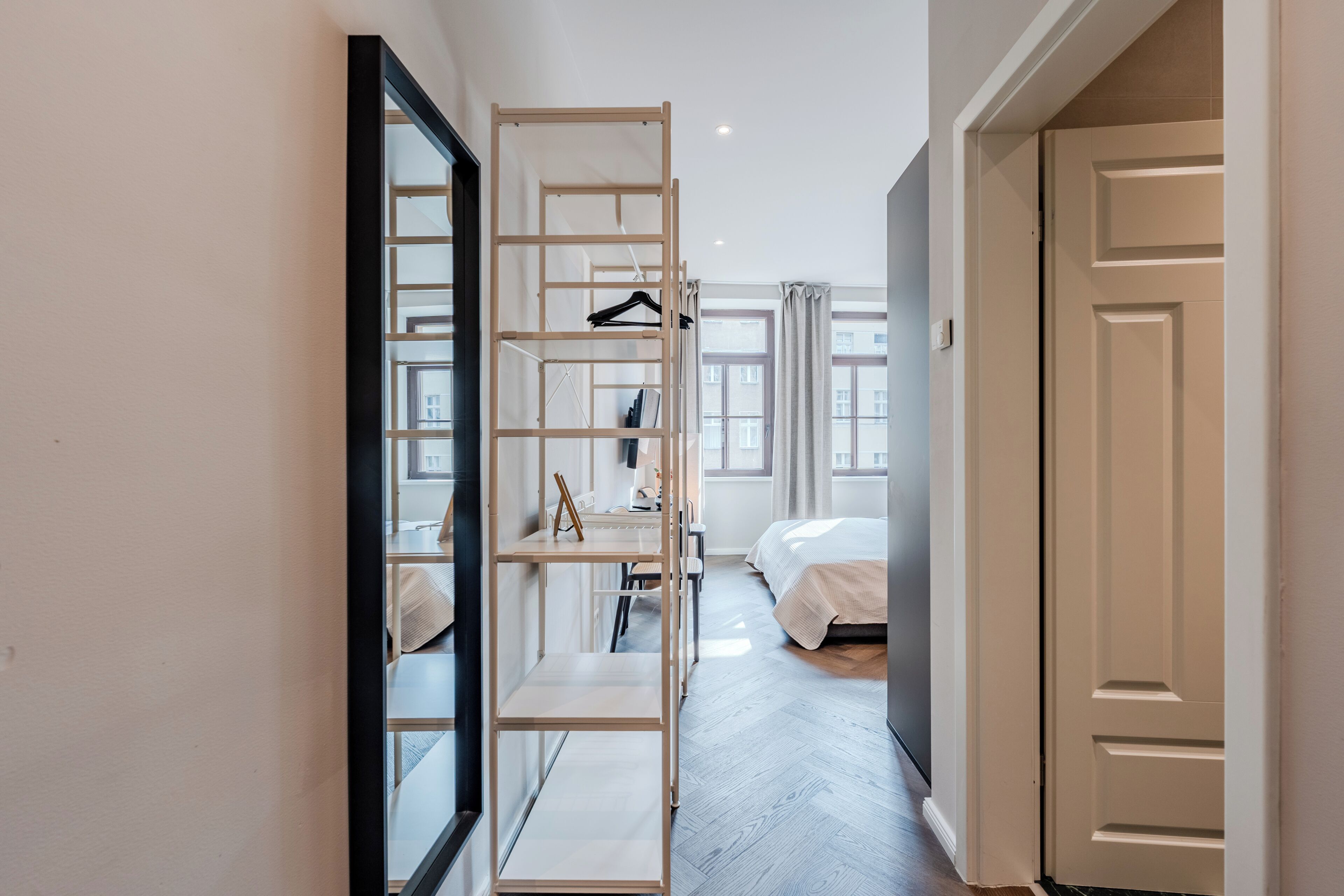 Ein Flur mit einem Spiegelkleiderschrank, einem Bett und einer Tür zu einem anderen Raum.