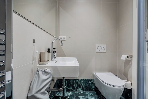Een moderne badkamer met een wit wastafelmeubel, toilet en douchehoek.