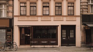 En bygning med flere etager, symmetrisk facade, jævnt placerede vinduer og dekorative gesimser.