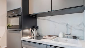Eine moderne Küche mit Einbauofen, Wasserkocher und Spüle mit Marmorablage.