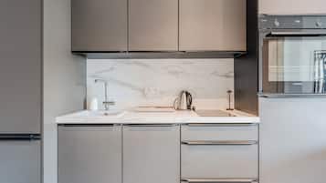 Une cuisine moderne avec des meubles gris, un pare-feu en marbre et des appareils électroménagers en acier inoxydable.