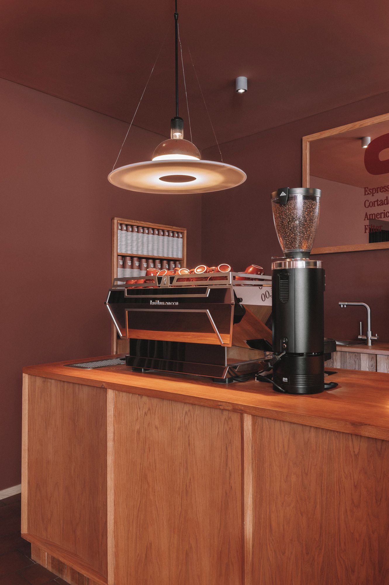 Una cafetería con un molinillo, una máquina de café y una exposición de tazas.