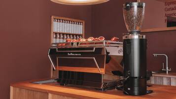 Una cafetería con un molinillo, una máquina de café y una exposición de tazas.