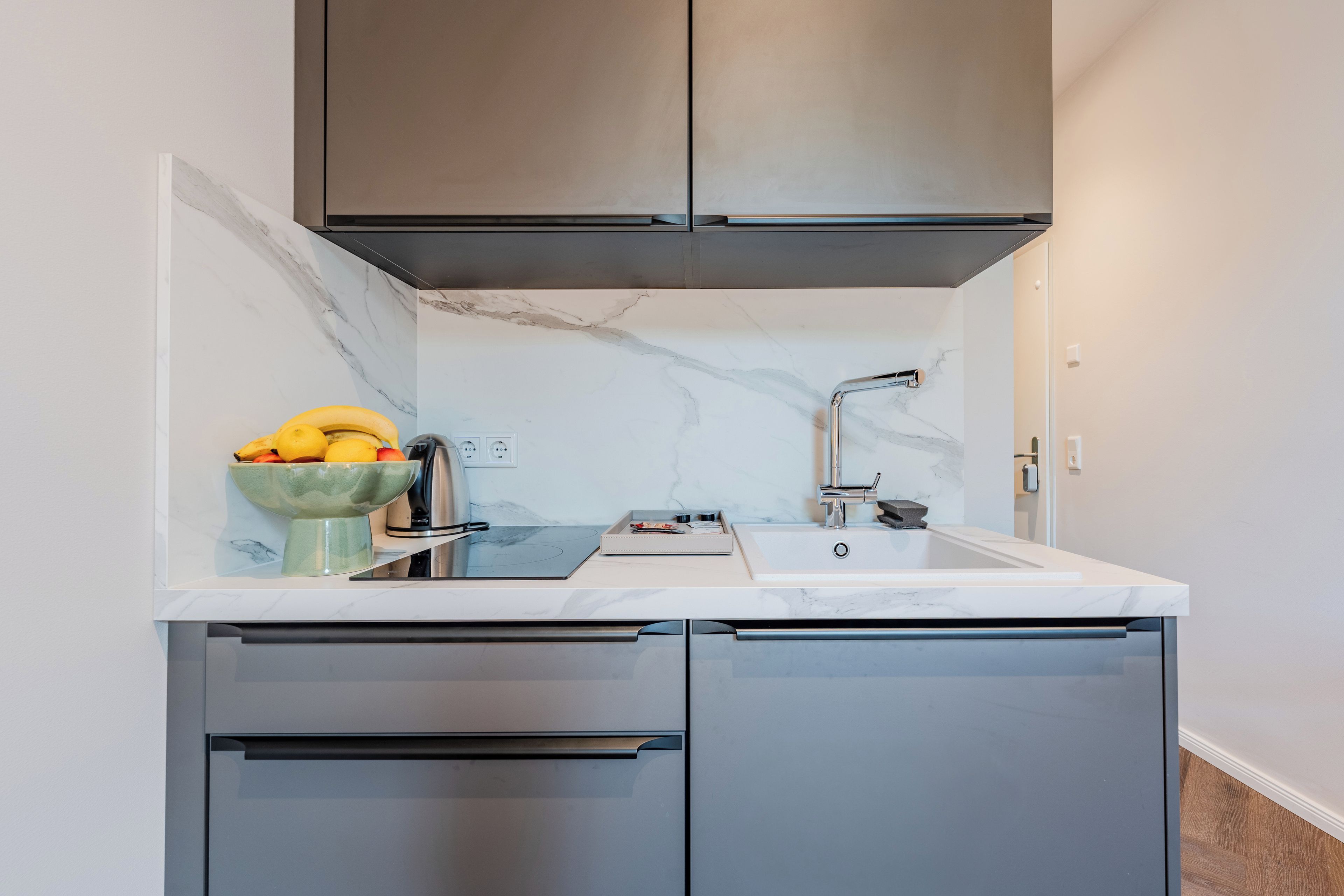 Una cocina compacta con estufa integrada, pileta y campana extractora de acero inoxidable.
