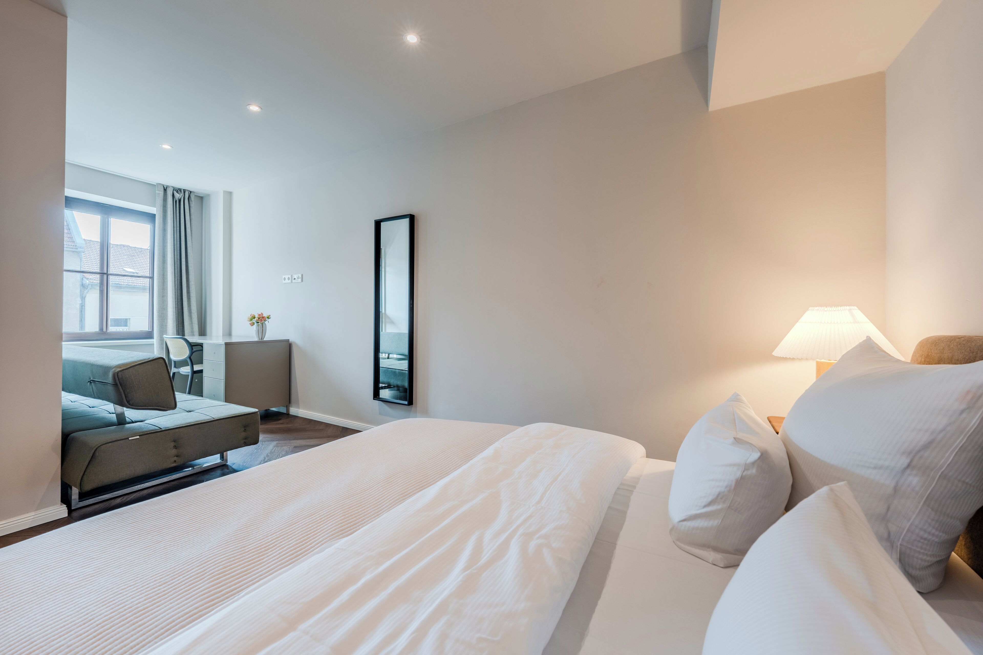 Una habitación de hotel con cama, escritorio, silla y ventana.