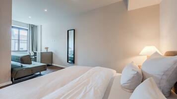Una habitación de hotel con cama, escritorio, silla y ventana.