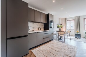 Eine moderne Küche mit dunklen Schränken, einer Marmor-Spritzschutzwand und einem Essbereich mit rundem Tisch und Stühlen.