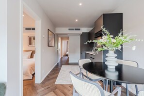 A modern dining area with a round table, chairs, and a vase of flowers. - LYV Apartments - Berlin Neukölln (Berlin)