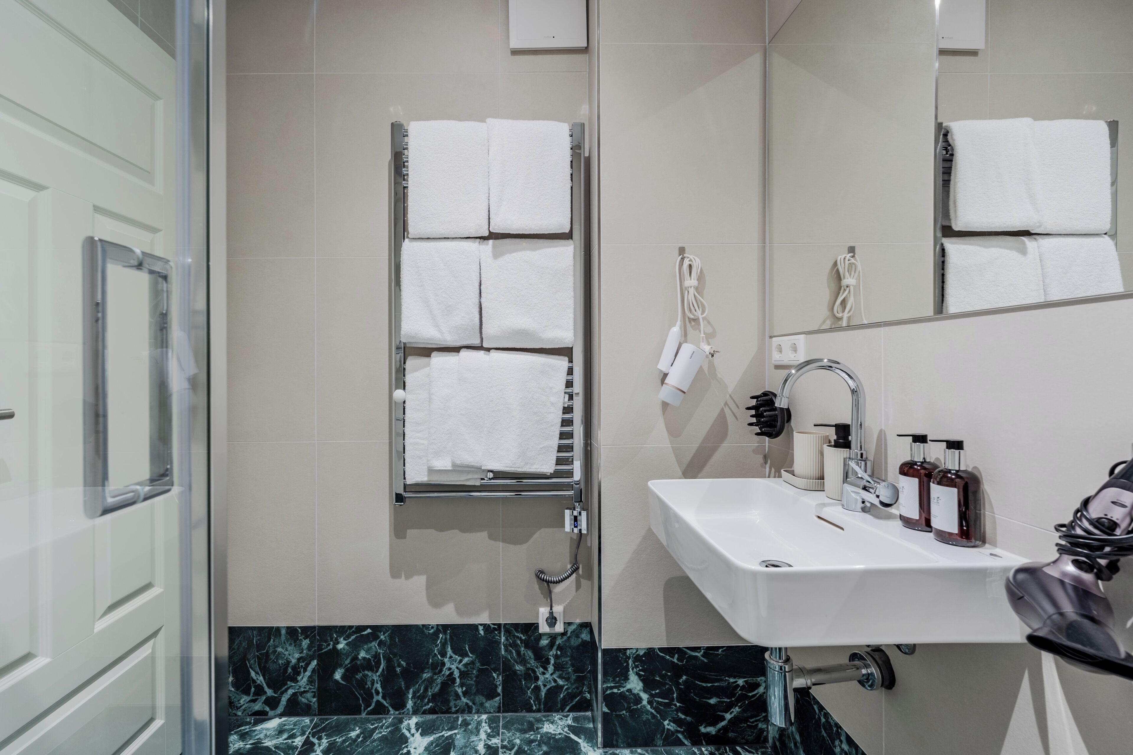 A bathroom with a white sink, a mirror, and a towel rack.