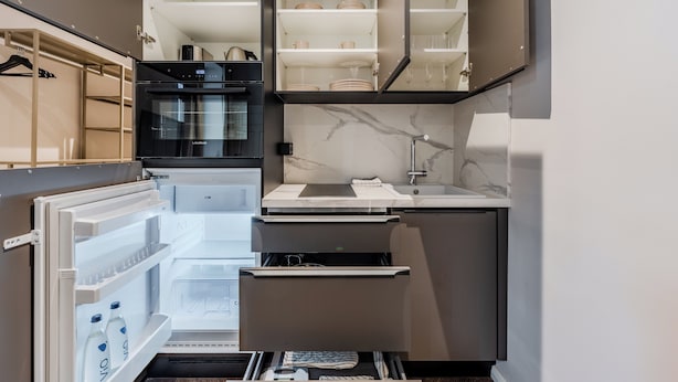 A compact kitchen with a built-in refrigerator, a microwave, and a sink. - LYV Apartments - Berlin Neukölln (Berlin)