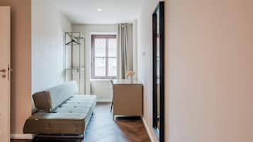 Ein Flur mit einer Couch, einem kleinen Tisch mit einer Vase und einer Tür.