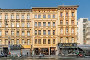 A row of historic buildings with ornate facades, a street with parked bicycles, and a clear blue sky. - LYV Apartments - Berlin Neukölln (Berlin)