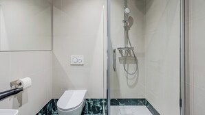 Ein modernes Badezimmer mit Duschkabine aus Glas, Toilette und Marmorboden.