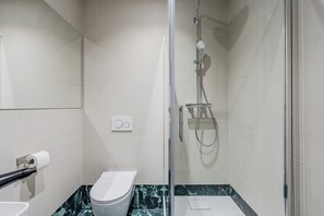 Ein modernes Badezimmer mit Duschkabine aus Glas, Toilette und Marmorboden.