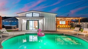 Ein modernes Haus mit Swimmingpool, Außenbereich zum Sitzen und einer Terrassenfläche.