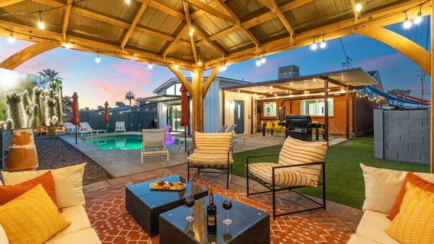Eine überdachte Terrasse im Freien mit Sitzgelegenheiten, einem Pool und einem Grillbereich.