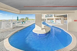 A swimming pool with a tiled edge, lounge chairs, and a view of the ocean. - 14th floor 4BR/3BA Ocean Front Condo: Stunning Views & Upgraded Ocean Bay Club (North Myrtle Beach)