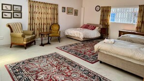 Un dormitorio con dos camas, una silla, una mesa y un ventanal con cortinas.