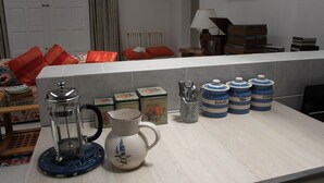 Una encimera de cocina con cafetera, jarra y recipientes de azúcar, té y café.