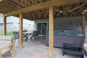 An outdoor patio with a hot tub, wooden pergola, and a table with chairs. - Family Fun Oasis: Pool, Hot Tub, Arcade & Ninja Course with 4 Bedrooms! (Omaha)