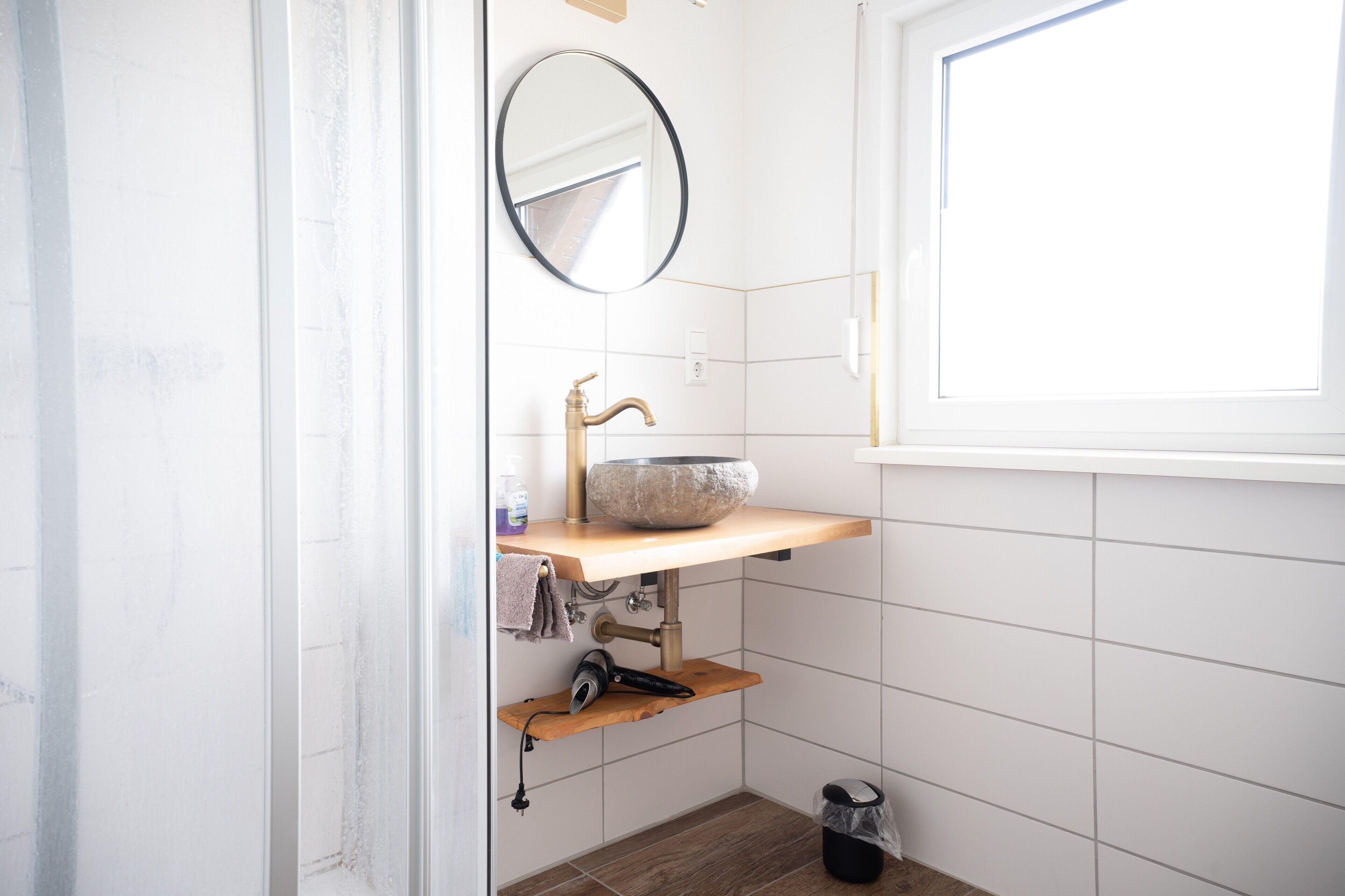 A bathroom with a stone sink, a mirror, a towel, and a hairdryer.