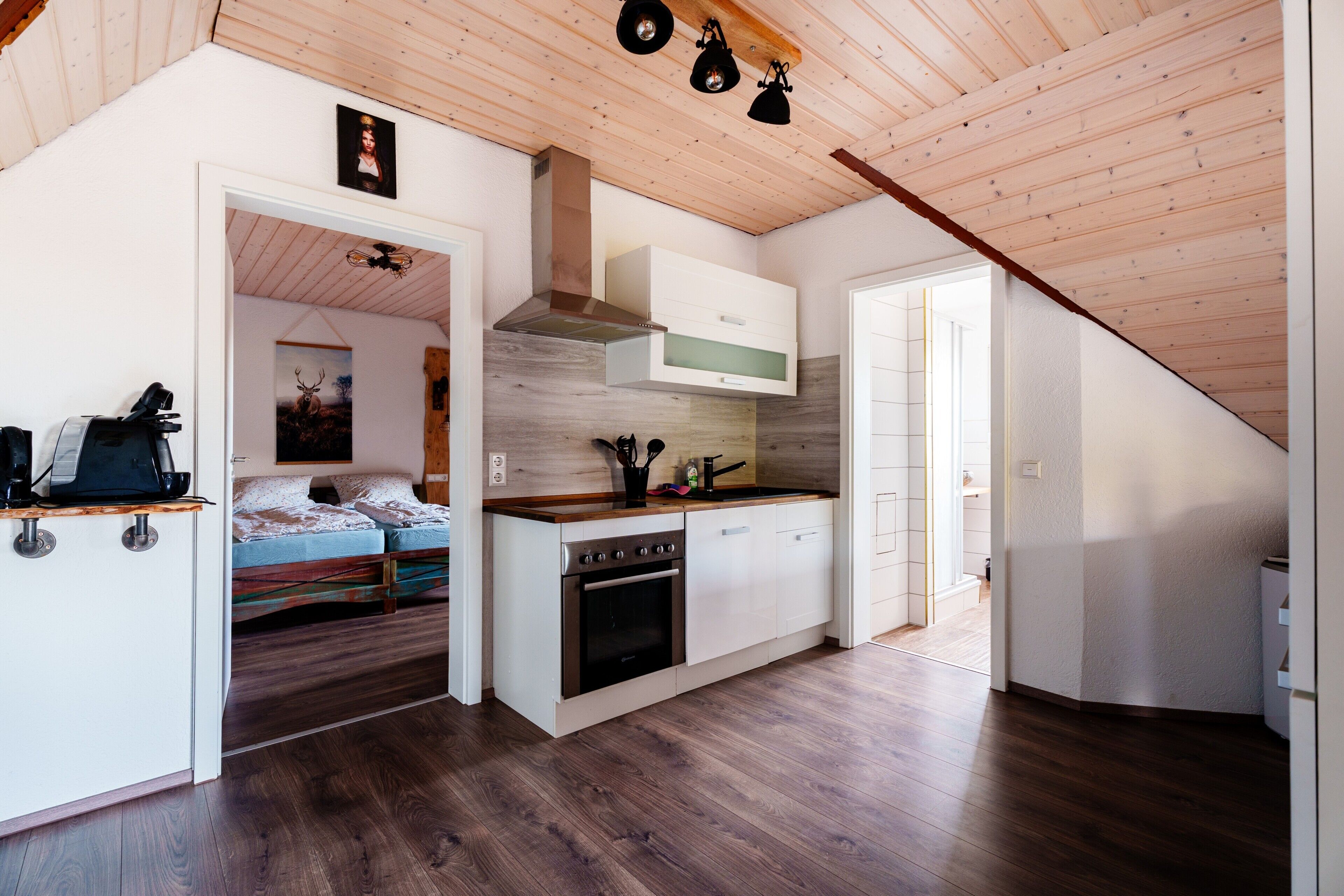 A compact kitchen with wooden flooring, a built-in oven, and a small dining area.