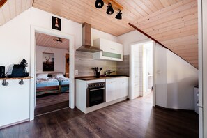 Uma cozinha compacta com piso de madeira, forno embutido e um pequeno espaço de refeições.