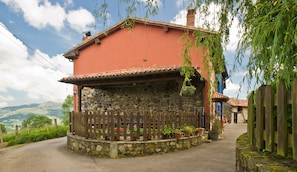 A rustic house with a stone foundation, a wooden fence, and potted plants. - Rural House 'Casa Remis' in Piloña – Sleeps 12, Private Bathrooms, Fireplace (Piloña)