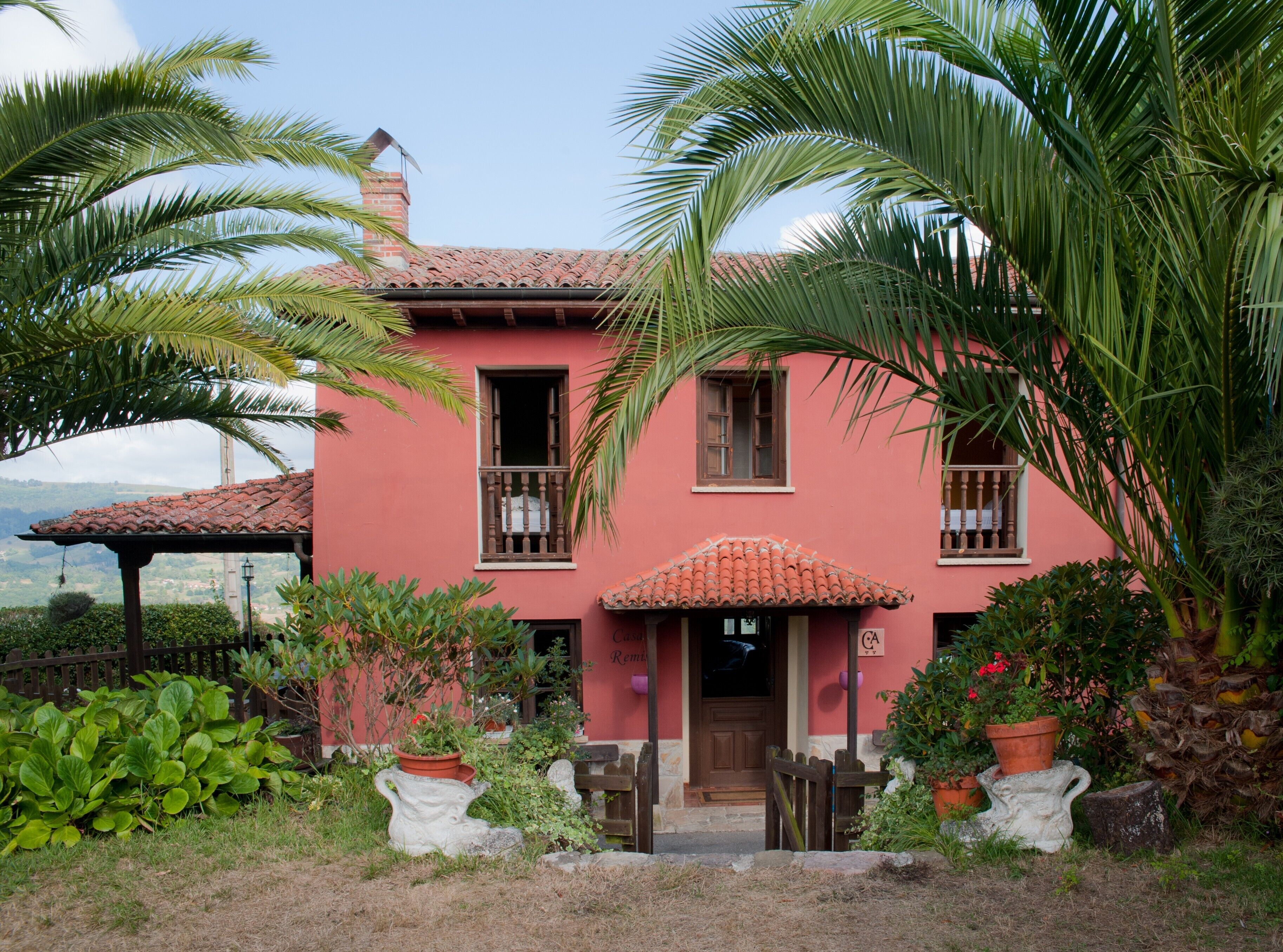 Un bâtiment rose avec un toit en tuiles, un balcon en bois et une porte portant l’inscription « Remise ».