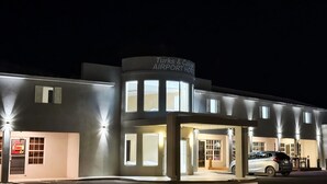 Un edificio con un letrero que dice "Turks & Caicos Airport Hotel". Tiene varias ventanas y un coche estacionado en la parte delantera.