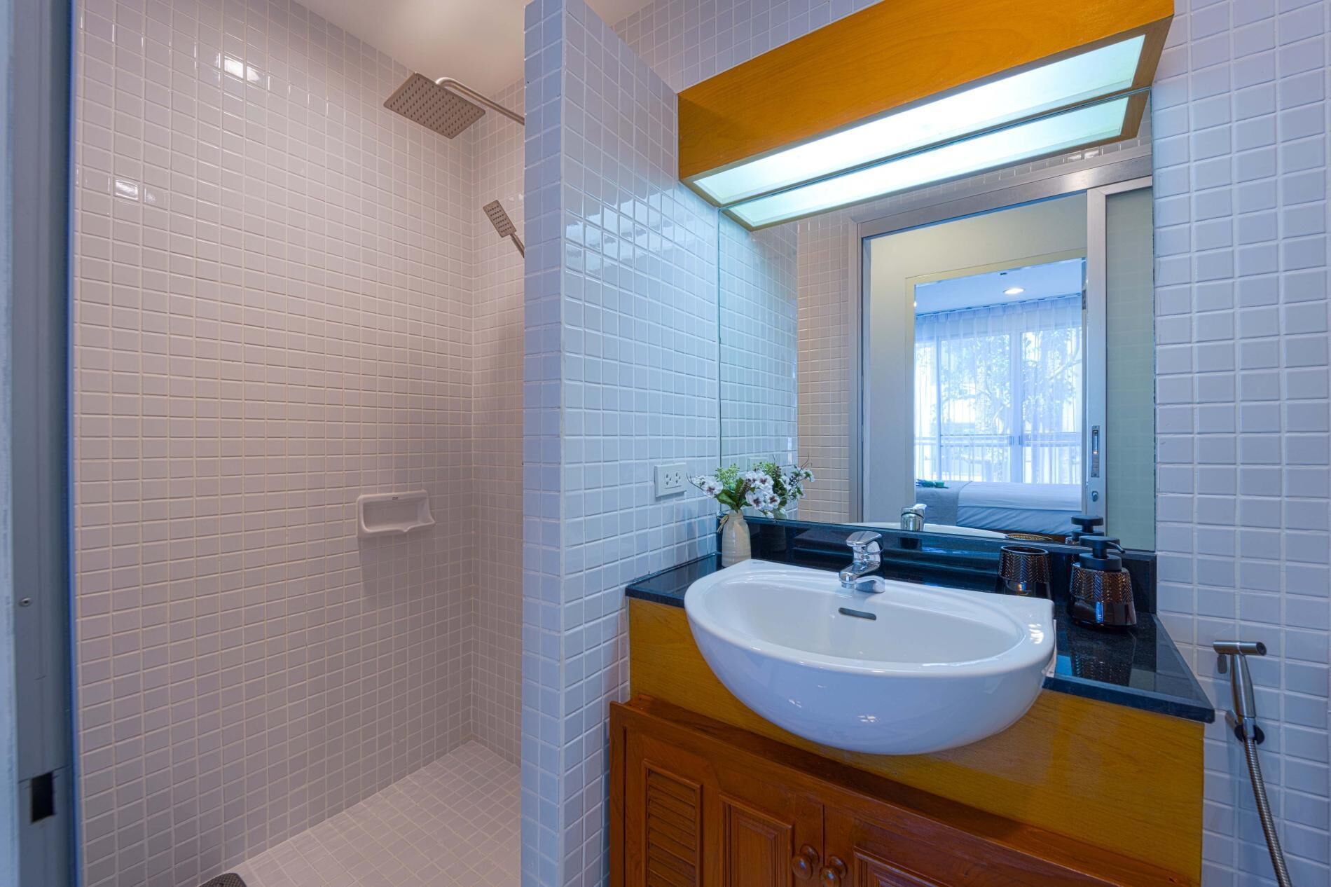 Un baño con lavamanos blanco, espejo y ducha.