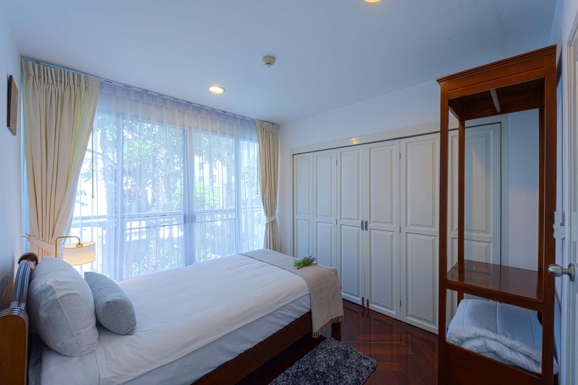 Un dormitorio con cama, armario y ventana con cortinas.