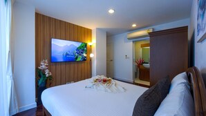 Habitación de hotel con una cama grande, un televisor montado en la pared y un baño visible a través de una puerta abierta.