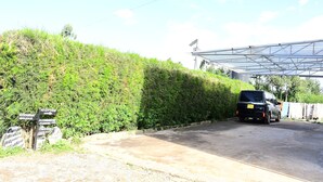 Uma área de estacionamento com um SUV preto, uma placa de recepção e um edifício com teto de vidro.