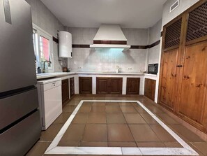 A kitchen with a central island, white cabinets, and a wooden door. - Villa Brisa Beach with Grill & Pool Málaga (La Cala del Moral)