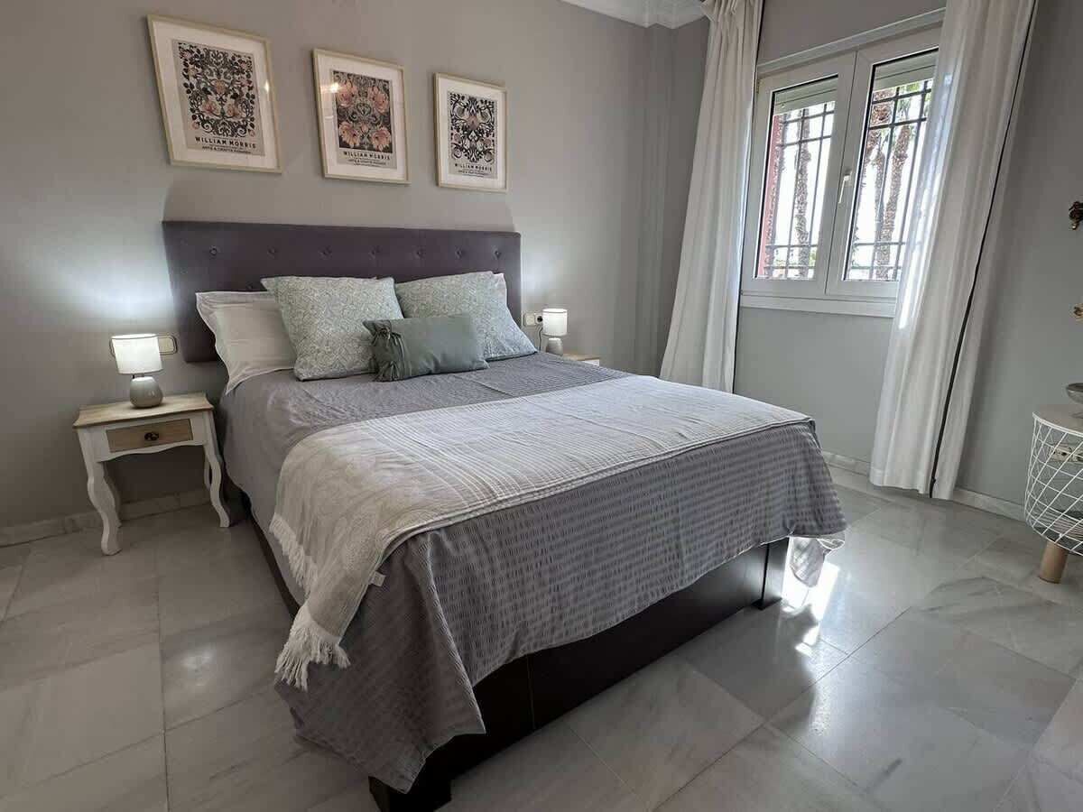 A neatly arranged bedroom with a large bed, two bedside tables, and a window with curtains.