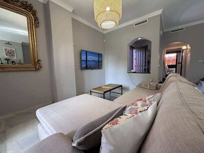 A modern bedroom with a large bed, a small table, a mirror, and a TV on the wall. - Villa Brisa Beach with Grill & Pool Málaga (La Cala del Moral)