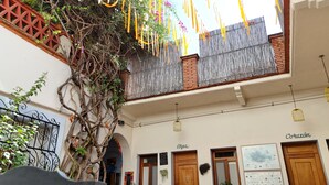 A courtyard with a decorative metal fence, a wooden door labeled "Arpa," and a sign with the word "Cozon." - El Diablo y la Sandia B&B (Oaxaca)